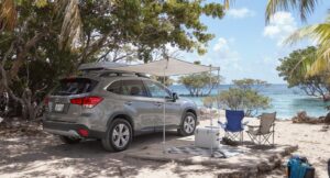 Organized car camping setup with SUV, canopy, and camping gear at a tropical Florida Keys State Park near calm blue water.